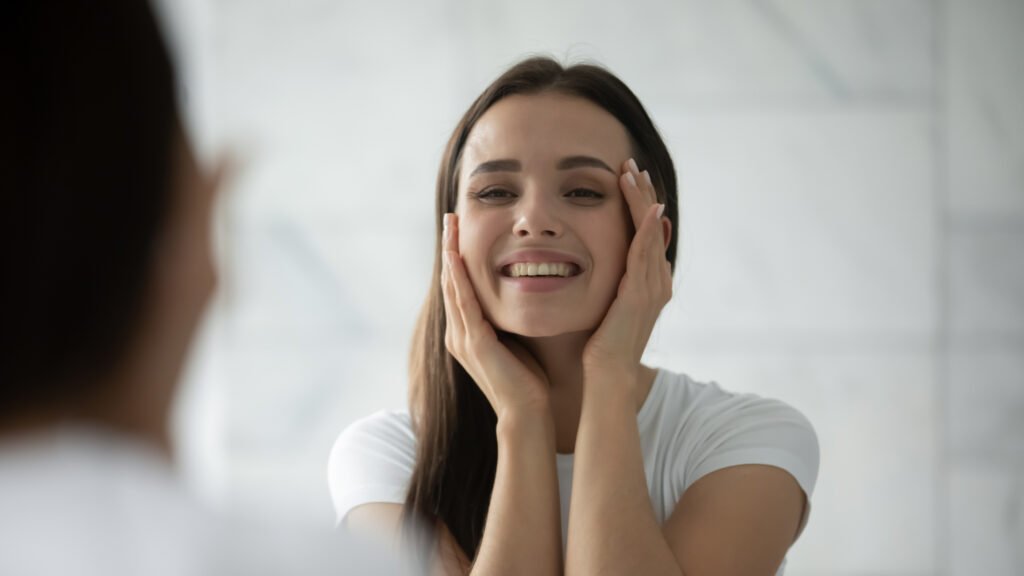 Woman smiling and touching her face after tear trough filler treatment