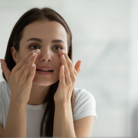 Woman assessing under eye hollows and tear trough area before treatment